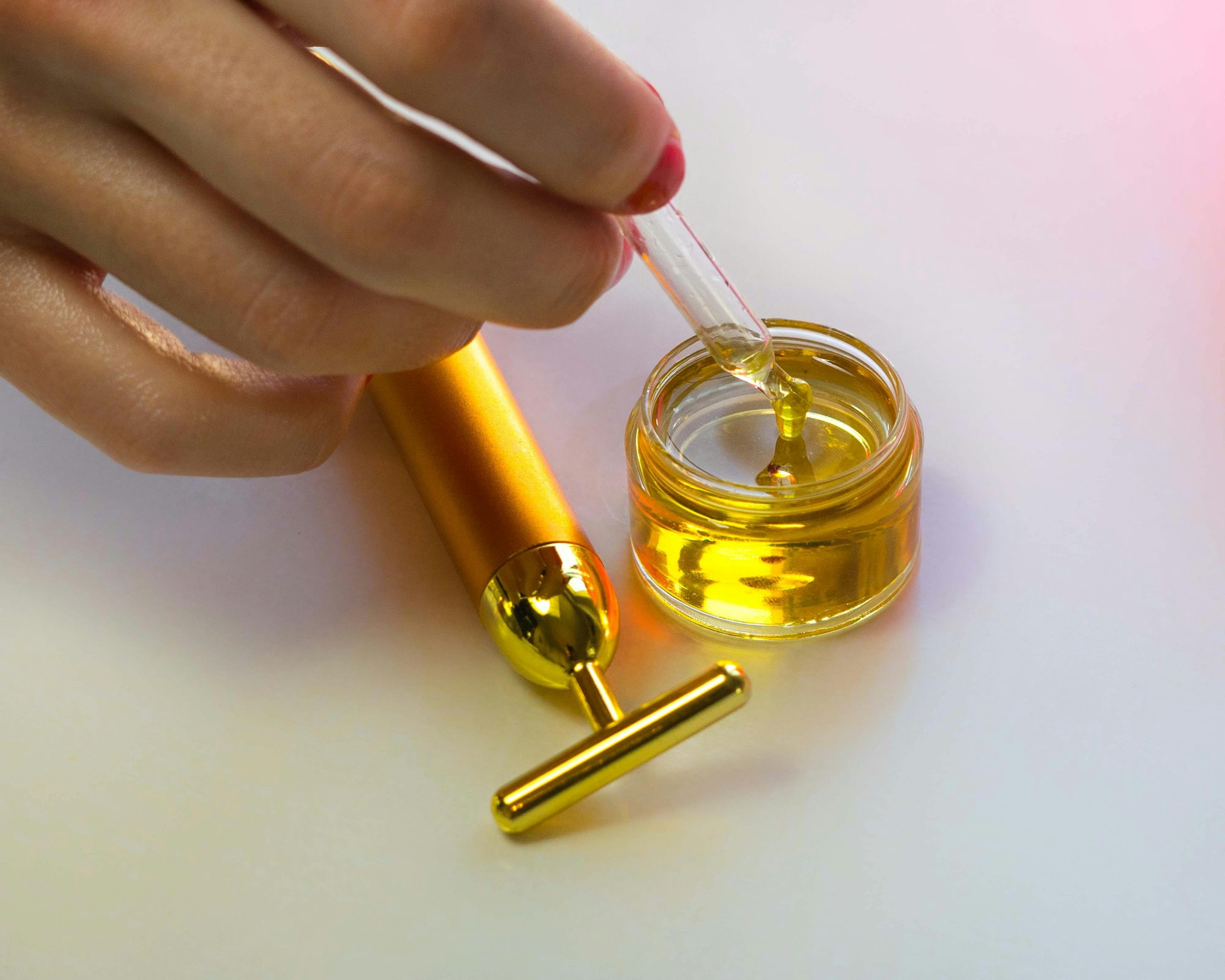 Close-up of a hand handling a serum dropper with massage tool showcasing luxury skincare routines.